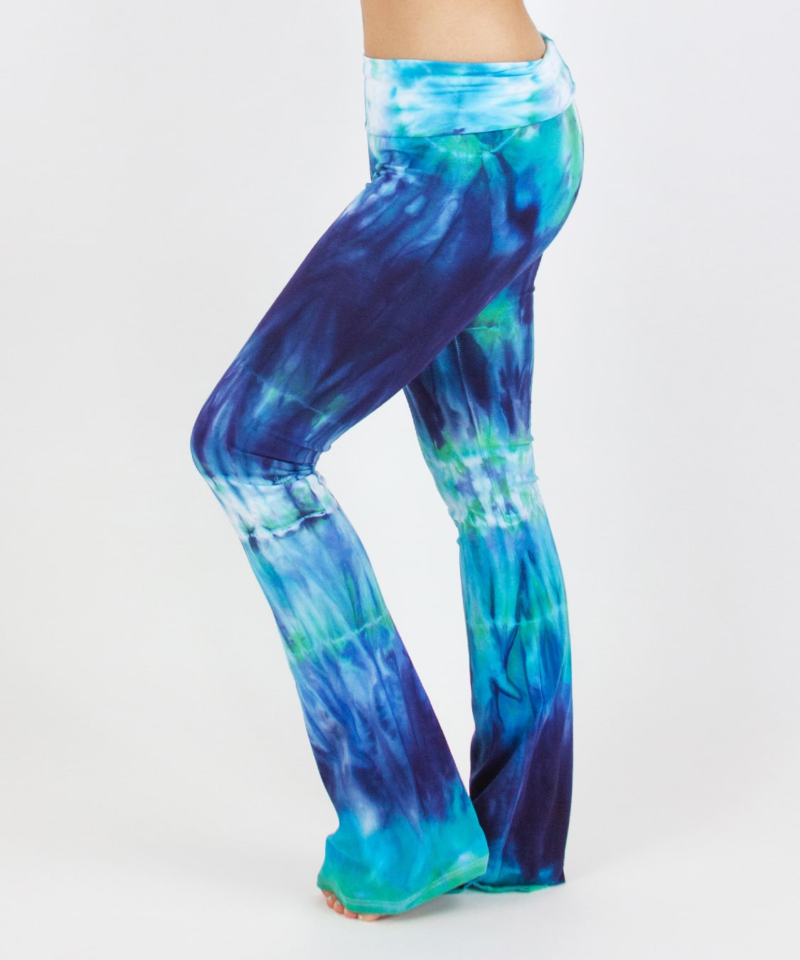 Woman wearing the Galapagos Islands tie dye yoga pants that features hand-dyed hues of navy blue, teal, and aqua.  These pants include a fold over waistband that is also comfortable as maternity wear.