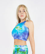 Woman wearing the Grenada tie dye crop top that features the colors aqua, green, and purple.