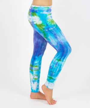 
                
                    Load image into Gallery viewer, Woman wearing the Grenada tie dye leggings that feature a fold over waistband.  The colors of the leggings include aqua, lavender, and emerald.
                
            