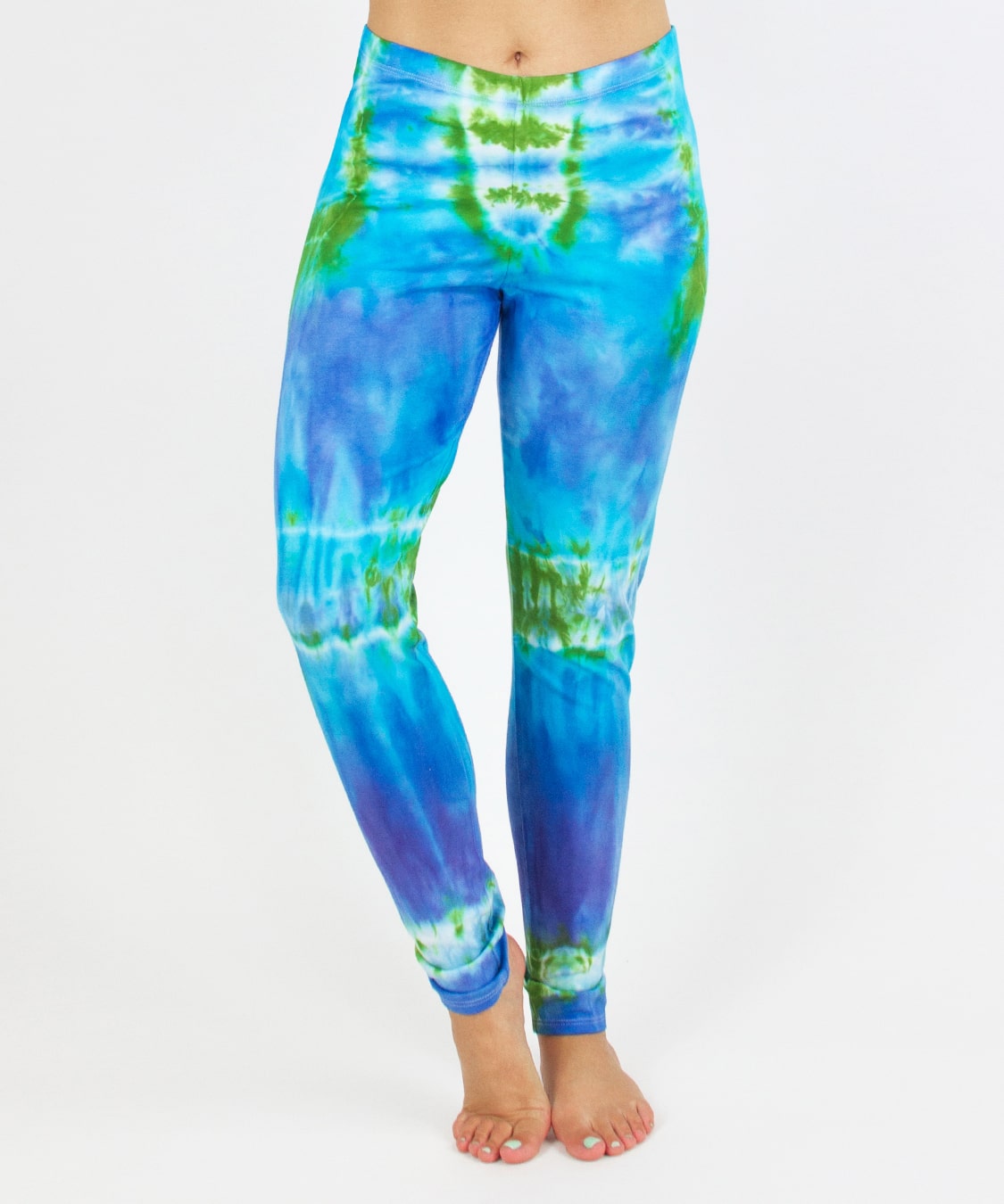 Woman wearing the Grenada tie dye leggings that feature hues of aqua, lavender, and emerald.