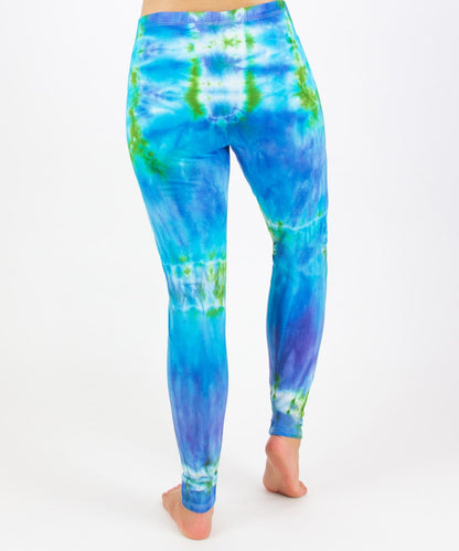 Woman wearing the Grenada tie dye leggings that feature hues of aqua, lavender, and emerald.