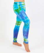 Woman wearing the Grenada tie dye leggings that feature hues of aqua, lavender, and emerald.