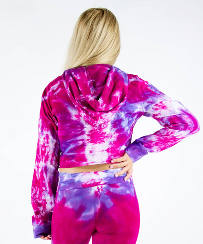 Woman wearing a pink and purple tie dye hoodie crop top.