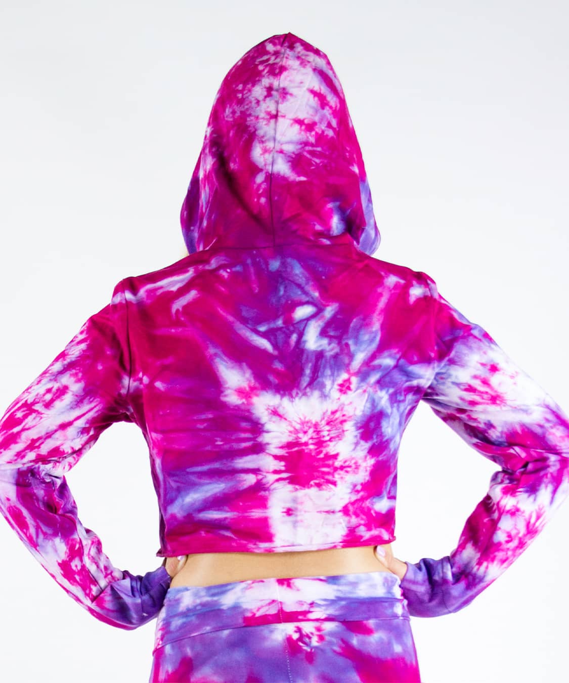 Woman wearing a pink and purple tie dye hoodie crop top.