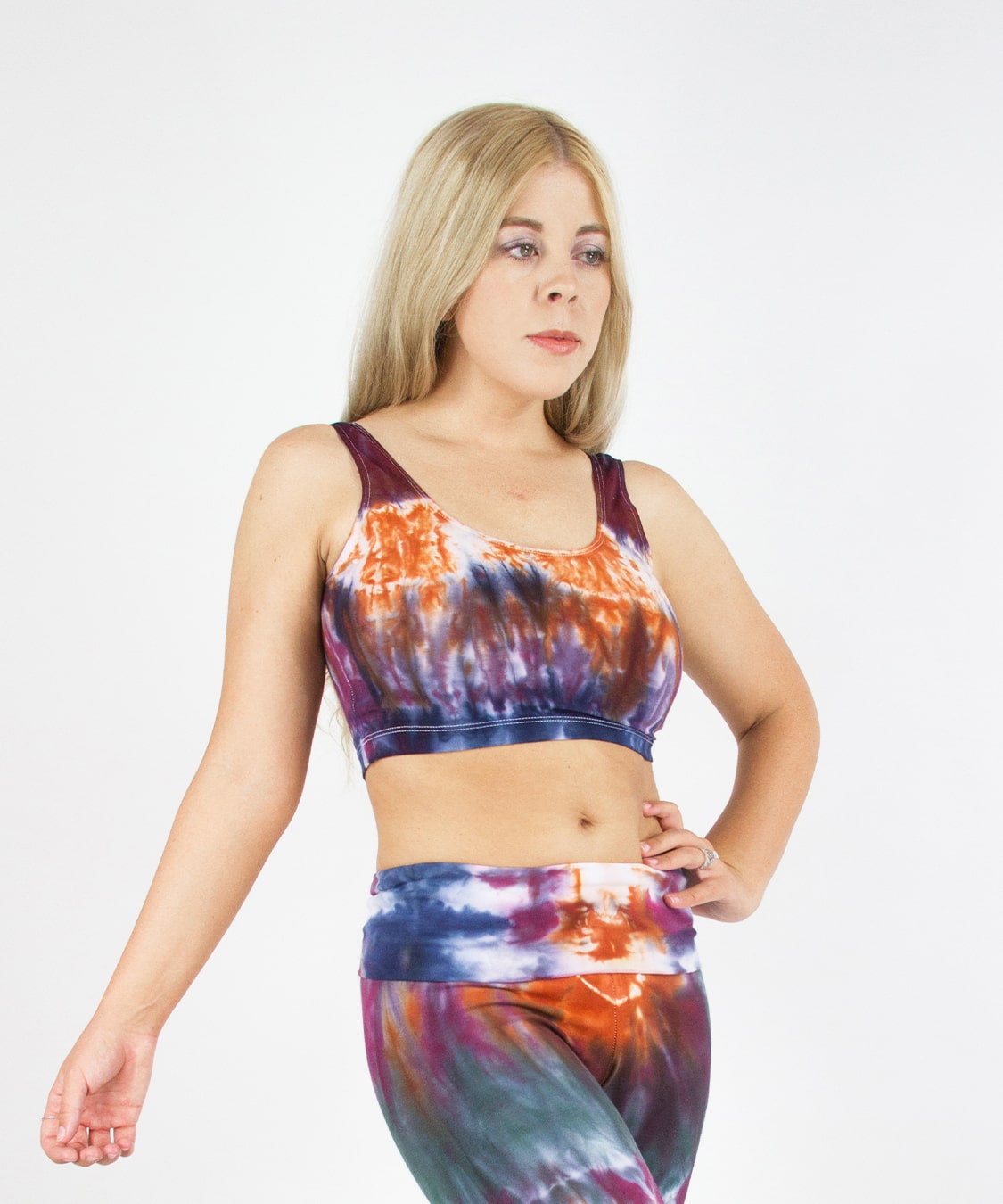 Woman wearing the Meteorite tie dye crop tank featuring a scoop neckline.  The colors in the crop top are orange, navy blue, purple, and dark green.