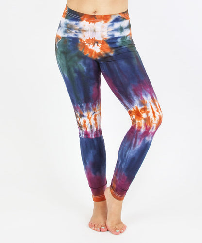 Woman wearing the Meteor tie dye leggings that feature the hues orange, navy, purple, and green.