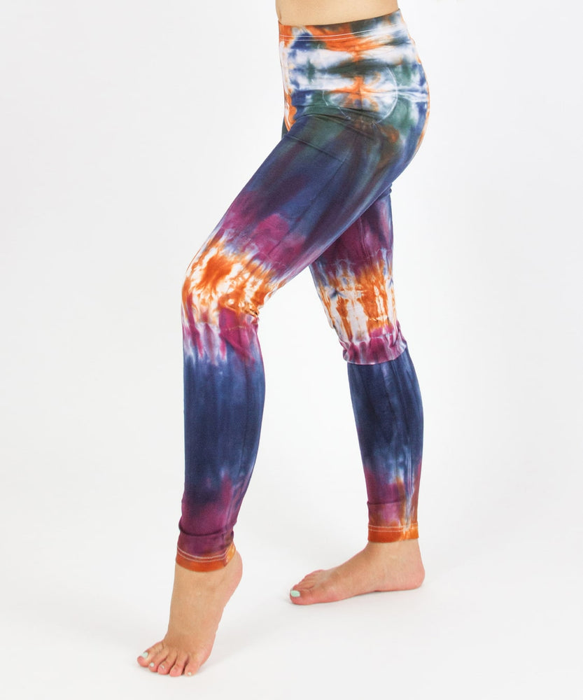 Woman wearing the Meteor tie dye leggings that feature the hues orange, navy, purple, and green.
