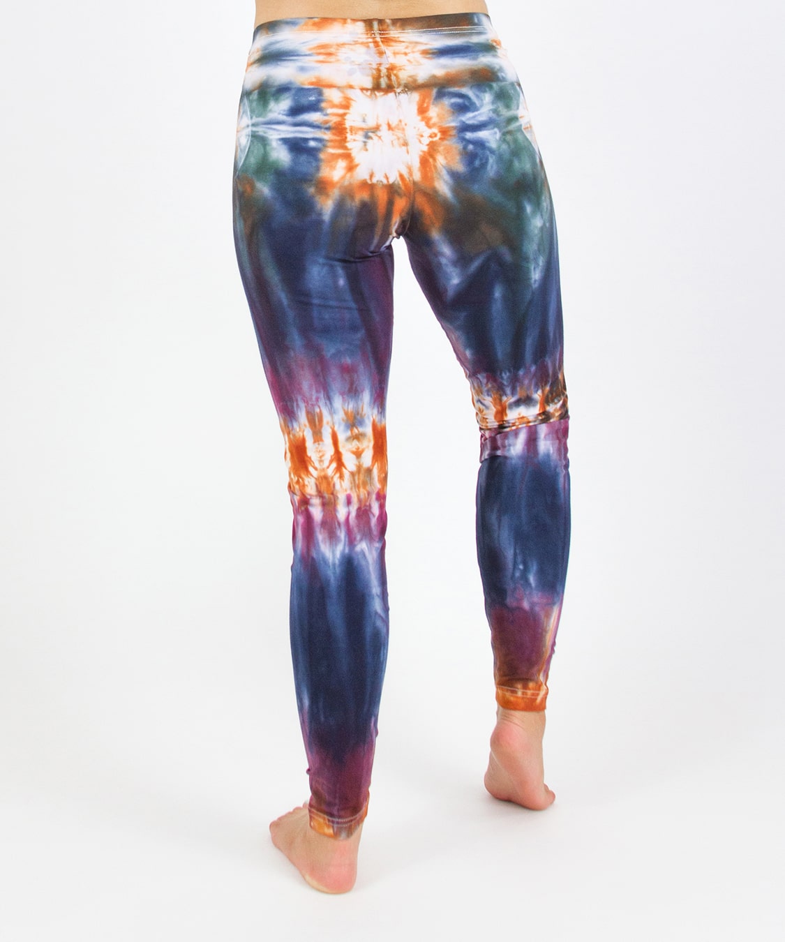 Woman wearing the Meteor tie dye leggings that feature the hues orange, navy, purple, and green.