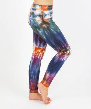 Woman wearing the Meteor tie dye leggings that feature the hues orange, navy, purple, and green.