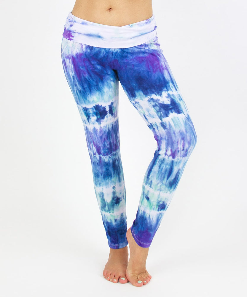 
                
                    Load image into Gallery viewer, Woman wearing the Mykonos tie dye leggings featuring a fold over waistband.  The colors in the pants include blue, light teal, purple, and white.
                
            