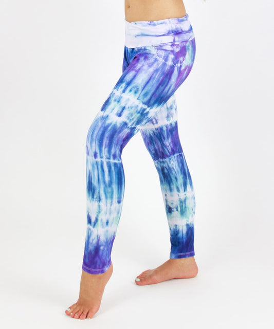 Woman wearing the Mykonos tie dye leggings featuring a fold over waistband.  The colors in the pants include blue, light teal, purple, and white.