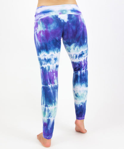 Woman wearing the Mykonos tie dye leggings featuring a fold over waistband.  The colors in the pants include blue, light teal, purple, and white.