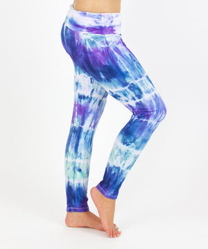 
                
                    Load image into Gallery viewer, Woman wearing the Mykonos tie dye leggings featuring a fold over waistband.  The colors in the pants include blue, light teal, purple, and white.
                
            