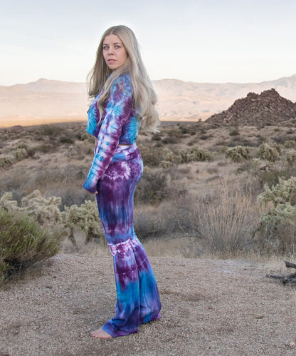 Woman wearing a pair of tie dye yoga pants and hoodie crop top.