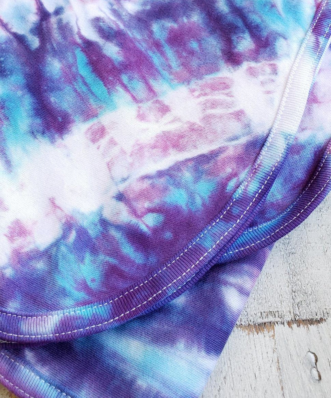 A purple and pink tie dye organic baby blanket with rounded corners.