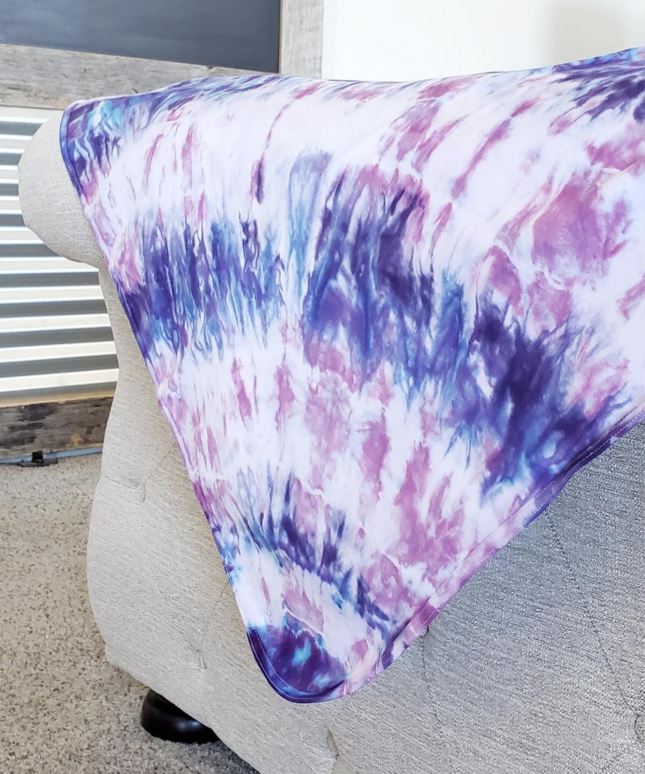 A purple and pink tie dye organic baby blanket with rounded corners.