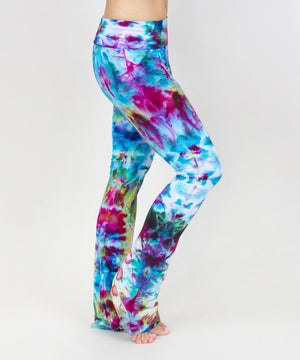 Woman wearing a pair of rainbow ice dye tie dye yoga pants with a fold over waistband.