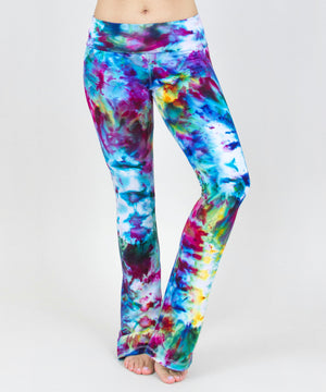 Woman wearing a pair of rainbow ice dye tie dye yoga pants with a fold over waistband.