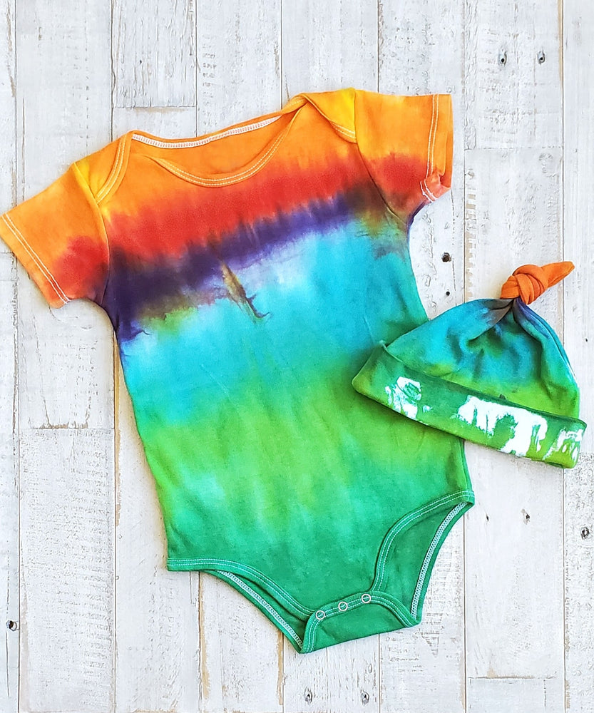 An organic tie dye baby bodysuit and hat in rainbow colors.