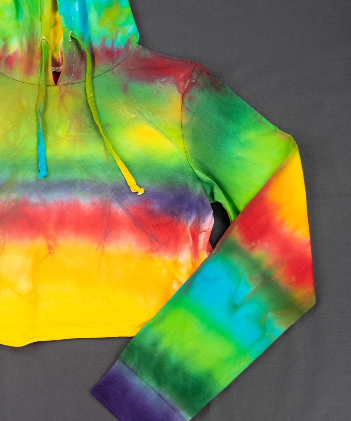 Rainbow tie dye hoodie crop top with a hood, drawstrings, and long sleeves.