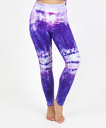 Woman wearing the Saint-Tropez tie dye leggings that feature a fold over waistband.  The colors in these pants include purple, pink, and white.