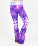 Woman wearing the Saint-Tropez tie dye yoga pants featuring the color purple, pink, and white.  The waistband can be folded down or up.