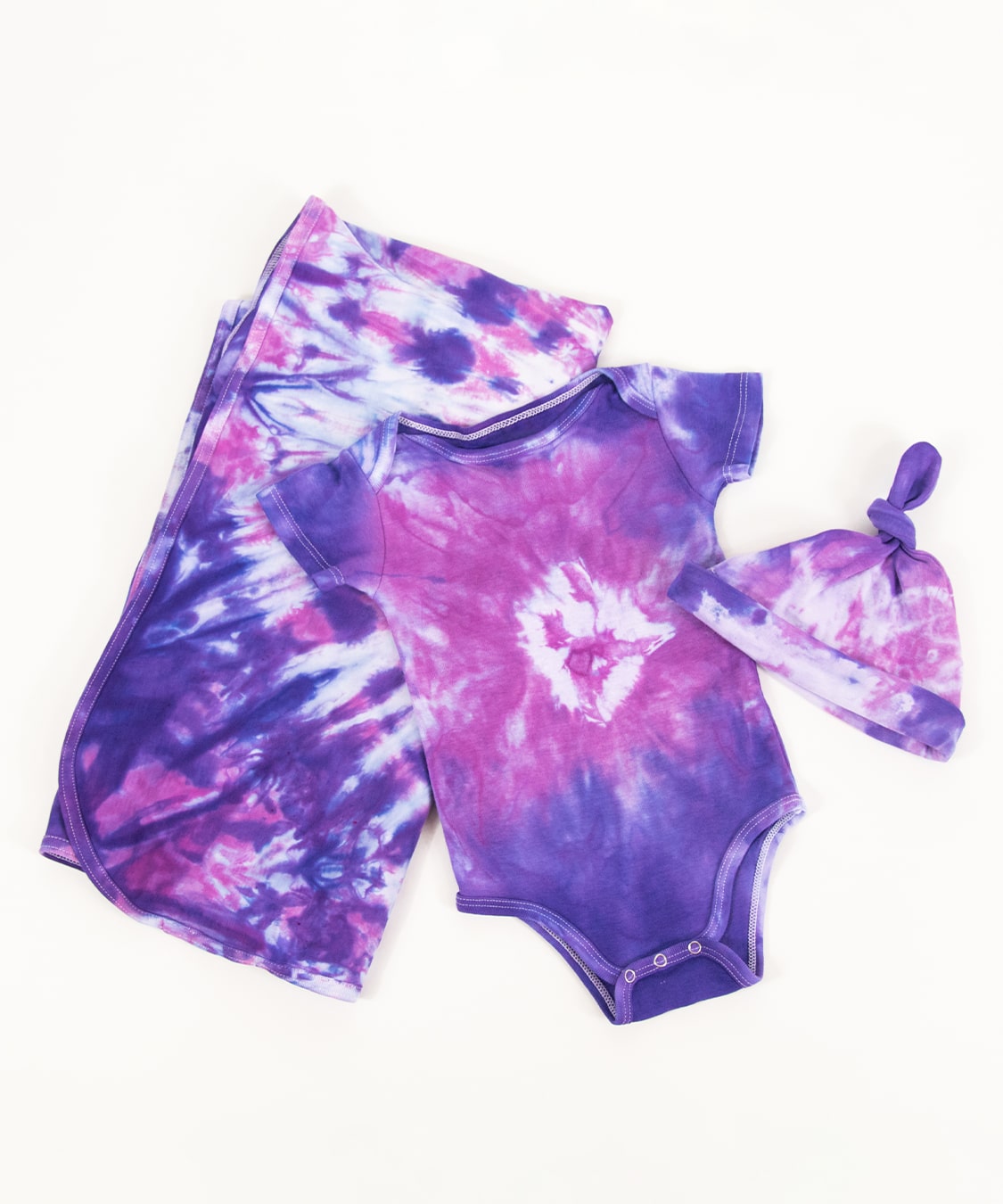 Pink and purple tie dye organic baby set that includes a baby blanket, onesie, and baby hat.