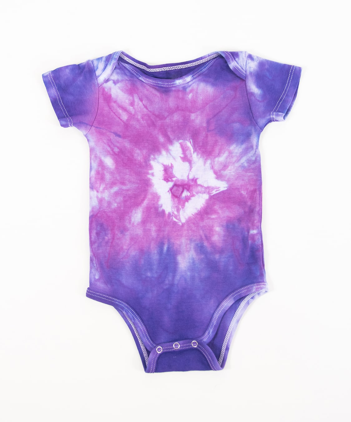 Pink and purple tie dye organic baby set that includes a baby blanket, onesie, and baby hat.