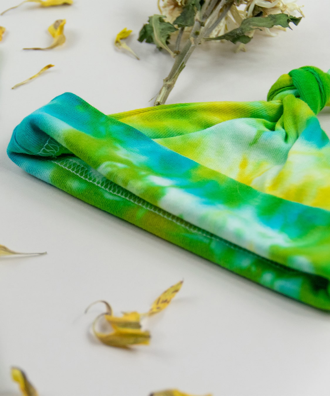 Green, yellow, and blue tie dye organic cotton baby bodysuit and hat set by Akasha Sun.