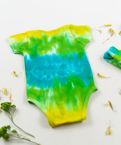 Green, yellow, and blue tie dye organic cotton baby bodysuit and hat set by Akasha Sun.