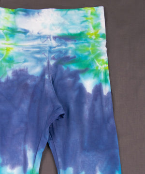 Teal, green, and blue tie dye yoga pants with a wide waistband and flare bottoms.
