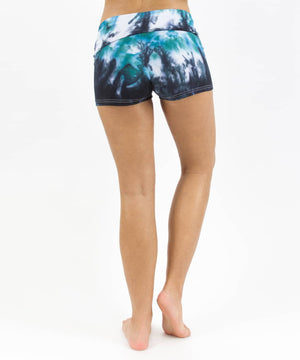 
                
                    Load image into Gallery viewer, Woman wearing a pair of teal and black tie dye fold over shorts made of sustainable cotton.
                
            