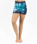 Woman wearing a pair of teal and black tie dye fold over shorts made of sustainable cotton.