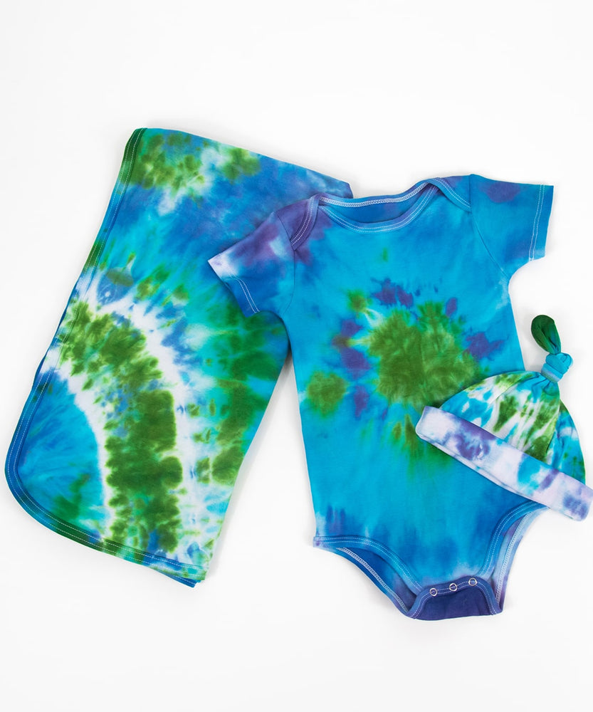 Blue and green tie dye baby gift set that includes an organic cotton baby blanket, baby hat, and onesie.