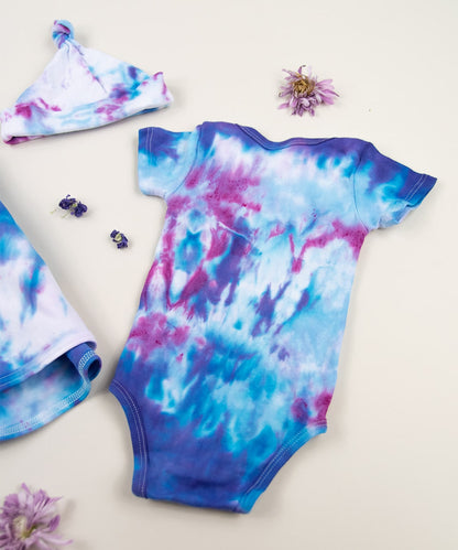 Blue and pink tie dye organic baby bodysuit, baby hat, and blanket set.