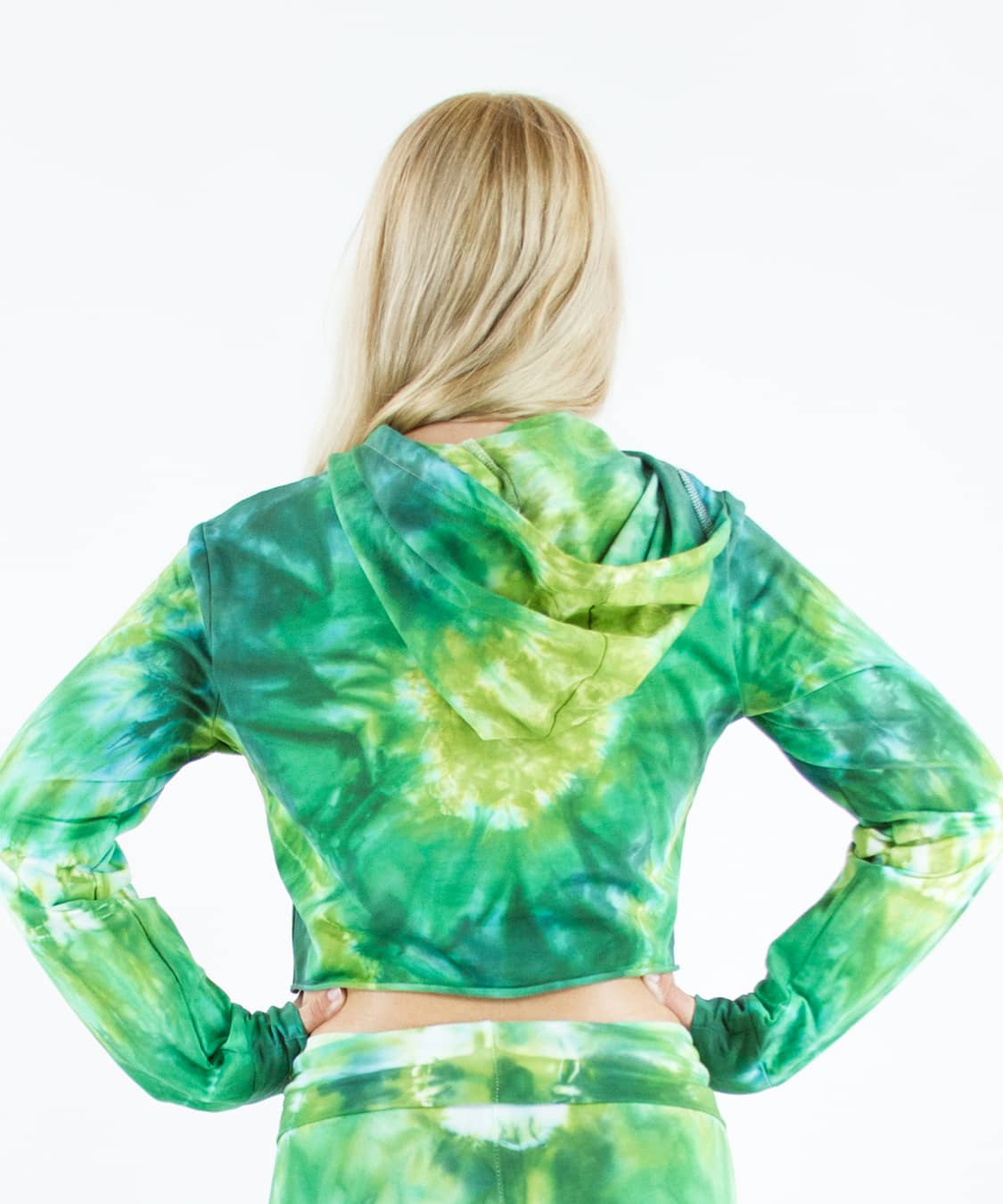 Woman wearing an Akasha Sun green tie dye crop top with a hood.